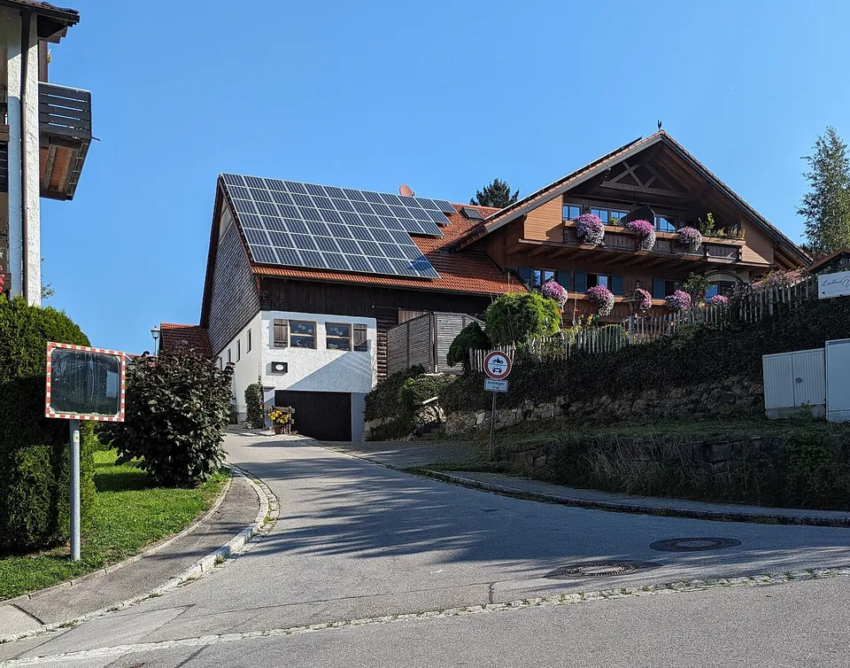 Bayerisches Landhaus mit Photovoltaikanlage auf dem Satteldach, Blumenkästen an den Balkonen